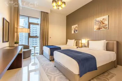 a hotel room with two beds and a desk at Staycae Avanti in Dubai
