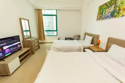 a hotel room with two beds and a flat screen tv at Masters and Double Rooms For Girls ONLY in Marina, Dubai in Dubai