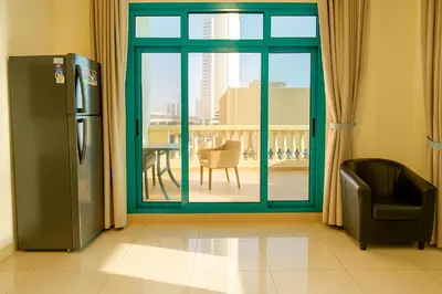 a room with a refrigerator and a view of a balcony at Masters and Double Rooms For Girls ONLY in Marina, Dubai in Dubai