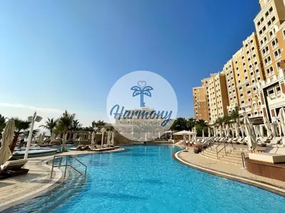 a swimming pool at a resort with a sign in the background at Harmony Vacation Homes - BALQIS Residence in Dubai