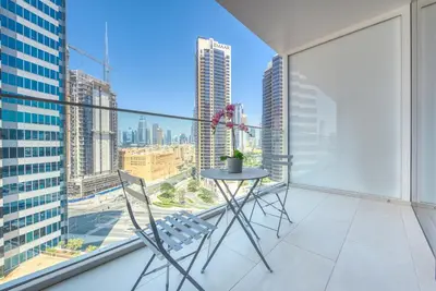 a table and chairs on a balcony with a view of the city at Maison Privee - Luxury, Spacious, Modern Near Burj Khalifa and Dubai Canal in Dubai