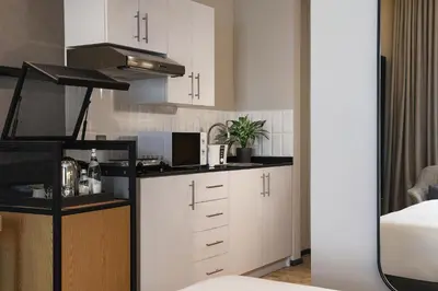 a kitchen with white cabinets and a microwave at JA The Manor Hotel, Dubai in Dubai