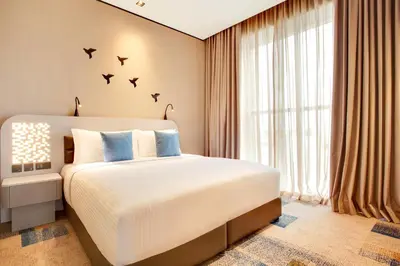 a bedroom with a large bed with birds on the wall at Lemon Tree Hotel, Jumeirah Dubai in Dubai