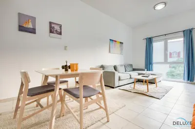 a living room with a table and chairs and a couch at Community Vibe Living with Wellness Access Close to Metro, Mediterranean, Discovery Gardens by Deluxe Holiday Homes in Dubai