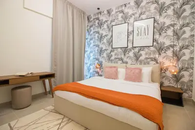 a bedroom with a bed with orange blanket and a wallpaper at Cozy 1BR Apart With Pool And Gym 10mins Away By drive to DXB Airport in Dubai
