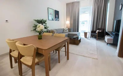 a living room with a dining room table and a couch at Cozy 1BR Apart With Pool And Gym 10mins Away By drive to DXB Airport in Dubai