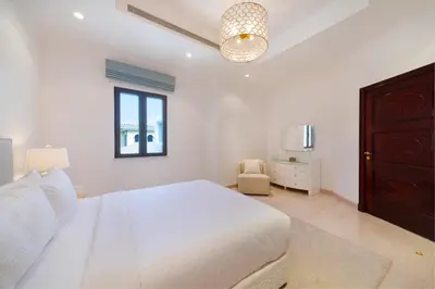 a white bedroom with a bed and a chandelier at Maison Privee - 5 Stars Villa with Private Pool or Beach on Palm Jumeirah in Dubai