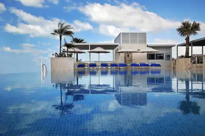 a swimming pool with blue chairs and umbrellas at Grand Cosmopolitan Hotel in Dubai