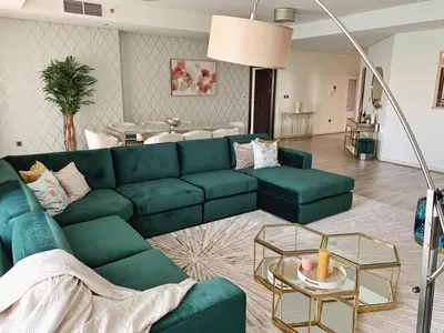 a living room with a green couch and a table at Luxury Apartments at Balqis Residence in Dubai