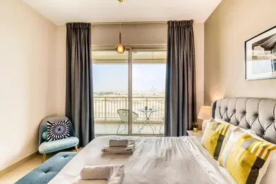 a bedroom with a bed and a balcony at GuestReady Holiday Homes - Sunny Delights in Dubai