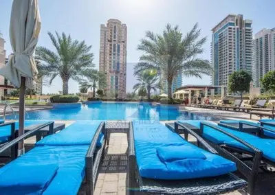 a large swimming pool with blue chairs and palm trees at GuestReady Holiday Homes - Sunny Delights in Dubai