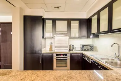 a kitchen with wooden cabinets and a sink at GuestReady Holiday Homes - Sunny Delights in Dubai