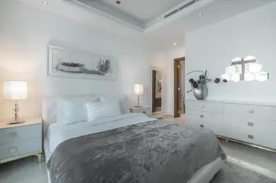 a white bedroom with a large bed and a dresser at HiGuests - Spacious 1BR in Dubai Marina With Amazing Views in Dubai