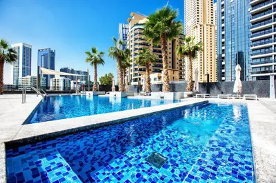 a large swimming pool with palm trees and buildings at Sparkle Tower, Dubai Marina in Dubai