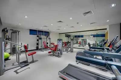 a gym with several treadmills and machines at URBAN Al Khoory Hotel in Dubai