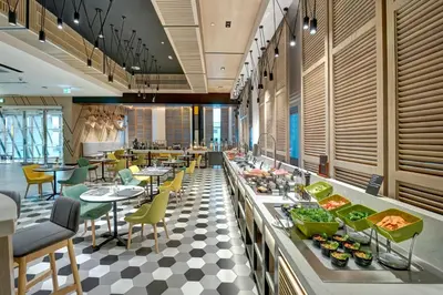 a restaurant with a buffet line with tables and chairs at URBAN Al Khoory Hotel in Dubai