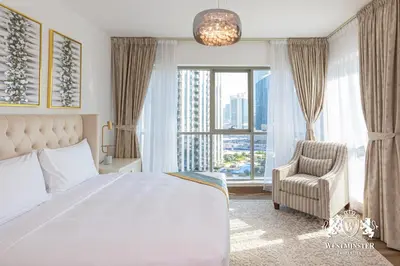 a bedroom with a bed and a chair and a large window at Westminster Boulevard Central - Burj Khalifa in Dubai