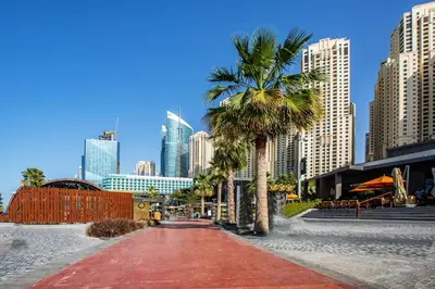 a palm tree and a red brick path in a city at 1 Bedroom with Stunning Ain Dubai and Full Sea View in Dubai