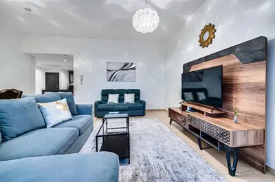 a living room with a blue couch and a tv at Wonderful 2BD apartment near The Beach Sadaf JBR in Dubai