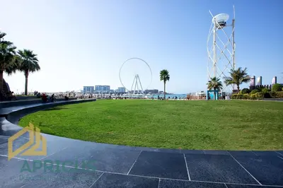 a grassy area with a ferris wheel in the background at Wonderful 2BD apartment near The Beach Sadaf JBR in Dubai