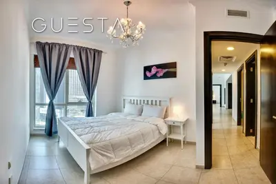 a white bedroom with a bed and a chandelier at Al Majara, Tower 1, Dubai Marina in Dubai