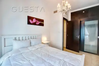 a bedroom with a white bed and a chandelier at Al Majara, Tower 1, Dubai Marina in Dubai