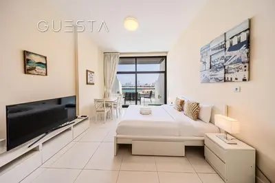 a white bedroom with a large bed and a tv at Club Vista Mare, free Riva beach club access in Dubai