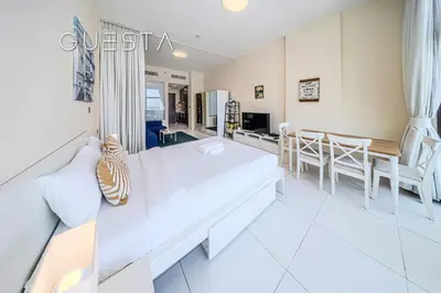 a living room with a white couch and a dining room at Club Vista Mare, free Riva beach club access in Dubai