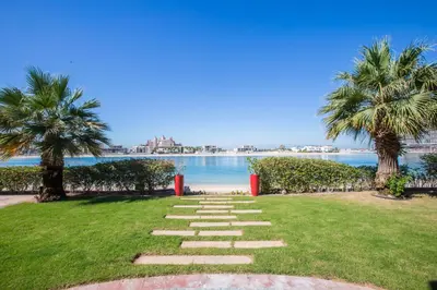 a stone path leading to the beach with palm trees at Maison Privee - Prvt Pool & Beach Access in Luxury Palm Jumeirah 6BR Villa in Dubai