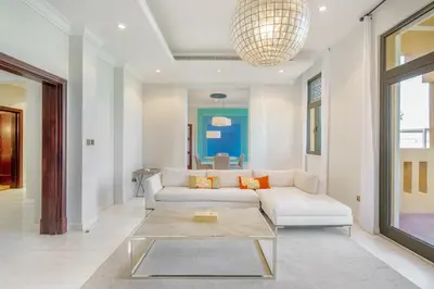 a living room with a white couch and a glass table at Maison Privee - Prvt Pool & Beach Access in Luxury Palm Jumeirah 6BR Villa in Dubai