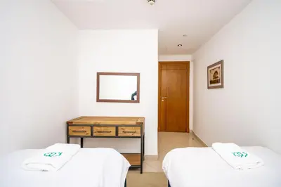 two beds in a room with a table and a mirror at Stylish and Sleek 1 Bed + Study near the JBR beach in Dubai