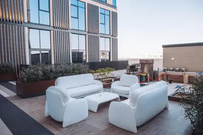 a group of white chairs and tables on a building at Staybridge Suites Dubai Al-Maktoum Airport by IHG in Dubai
