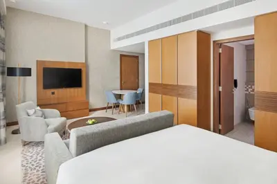 a hotel room with a bed and a living room at Staybridge Suites Dubai Al-Maktoum Airport by IHG in Dubai