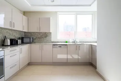 a white kitchen with white cabinets and a window at Frank Porter - Mon Reve in Dubai