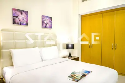 a bedroom with a white bed with a magazine on it at Staycae Holiday Homes - Suburbia in Dubai