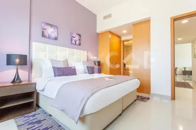a bedroom with a large bed with purple accents at Staycae Holiday Homes - Suburbia in Dubai