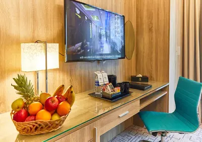a room with a television and a basket of fruit on a desk at Rose Plaza Hotel Al Barsha in Dubai