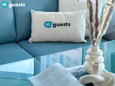 a blue couch with a pillow that reads its guess at HiGuests - Deluxe Apartment With Balcony and Amazing Views in Dubai
