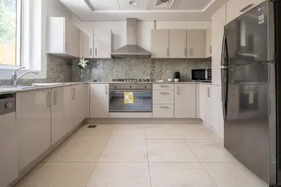 a kitchen with white cabinets and a stainless steel refrigerator at Frank Porter - Mon Reve in Dubai