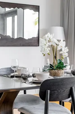 a dining table with glasses and a vase with white flowers at Island Paradise - Stylish 1BR on Bluewaters Island in Dubai