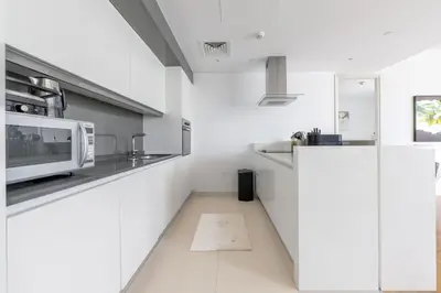 a white kitchen with a microwave on a counter at Island Paradise - Stylish 1BR on Bluewaters Island in Dubai