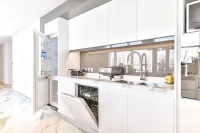 a white kitchen with white cabinets and a sink at Lavish & Equipped oceanfront 2 BR facing Ain Dubai in Dubai