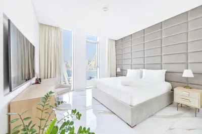 a bedroom with a white bed and a large window at Lavish & Equipped oceanfront 2 BR facing Ain Dubai in Dubai