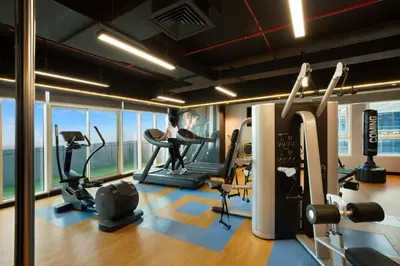 a gym with a woman on a treadmill in a building at Royal Continental Suites Business Bay - Deluxe Apartments in Dubai