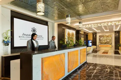 a man and a woman standing at a podium in a lobby at Royal Continental Suites Business Bay - Deluxe Apartments in Dubai