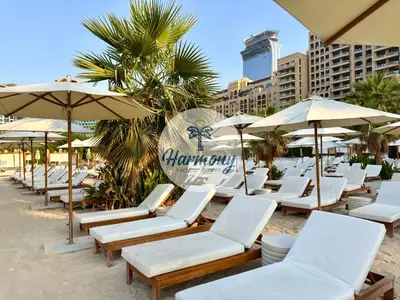 a row of lounge chairs and umbrellas on a beach at Harmony Vacation Homes - South Residence in Dubai