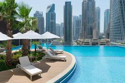 a pool with chairs and umbrellas and a city skyline at Jumeirah Living Marina Gate in Dubai