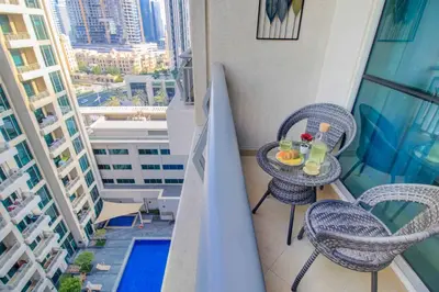 a balcony with two chairs and a table with drinks on it at Durrani Homes - Luxurious Studio near Dubai Mall with pool view in Dubai