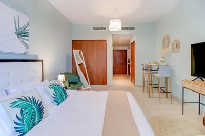 a bedroom with a white bed and a kitchen at Durrani Homes - Luxurious Studio near Dubai Mall with pool view in Dubai