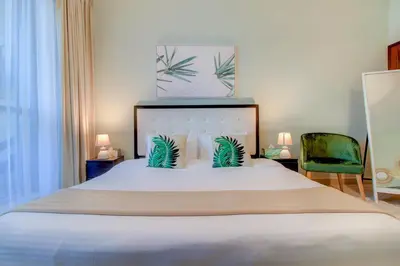 a bedroom with a large white bed with two chairs at Durrani Homes - Luxurious Studio near Dubai Mall with pool view in Dubai